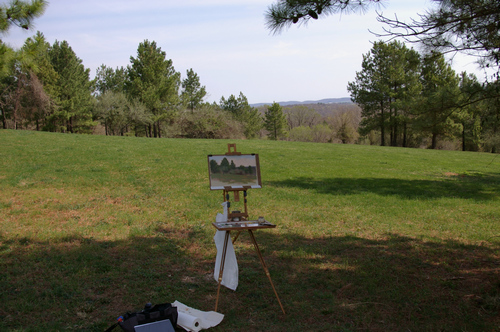 A photo showing a plein air painting setup in a field with Jullian half-box easel.