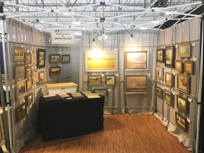 An indoor art fair booth with lighting, drapes and flooring