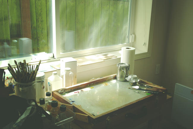 Artist's studio with pale green light coming in through a large window 